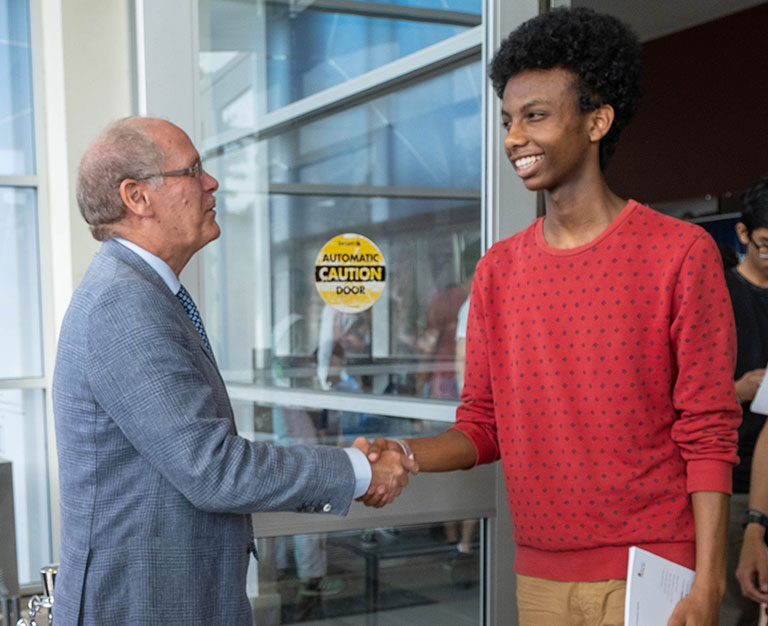 An image of David Farrar shaking hands with a Black student