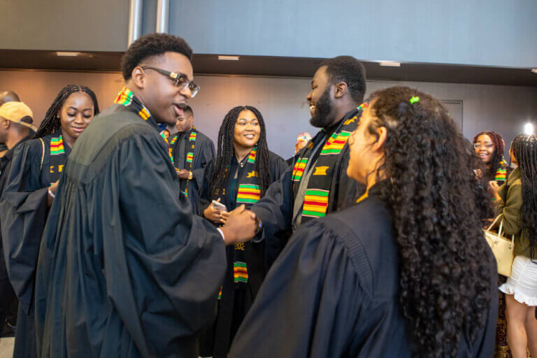 An image of Black graduates smiling and interacting