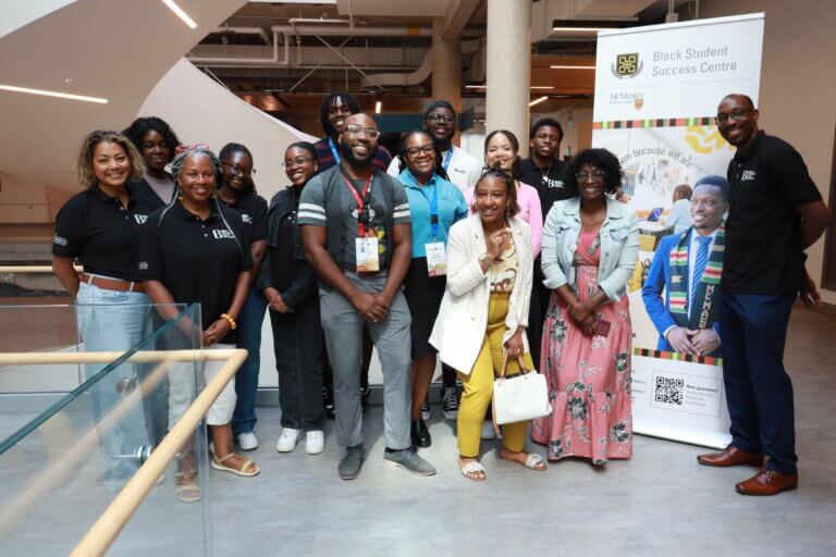 A group of people standing together inside a building with a banner for the Black Student Success Centre.